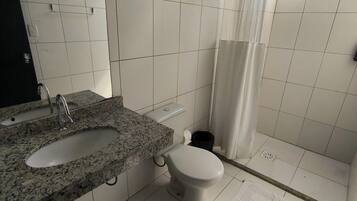 Ein Badezimmer mit einem Granitwaschbecken, einer weißen Toilette und einer Dusche mit weißem Vorhang.