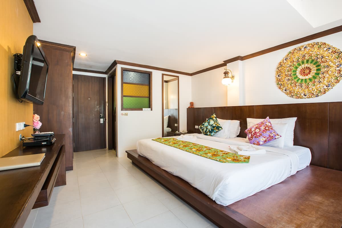 Camera d'albergo con un letto grande, una scrivania con un portatile, una TV e un elemento decorativo a parete.