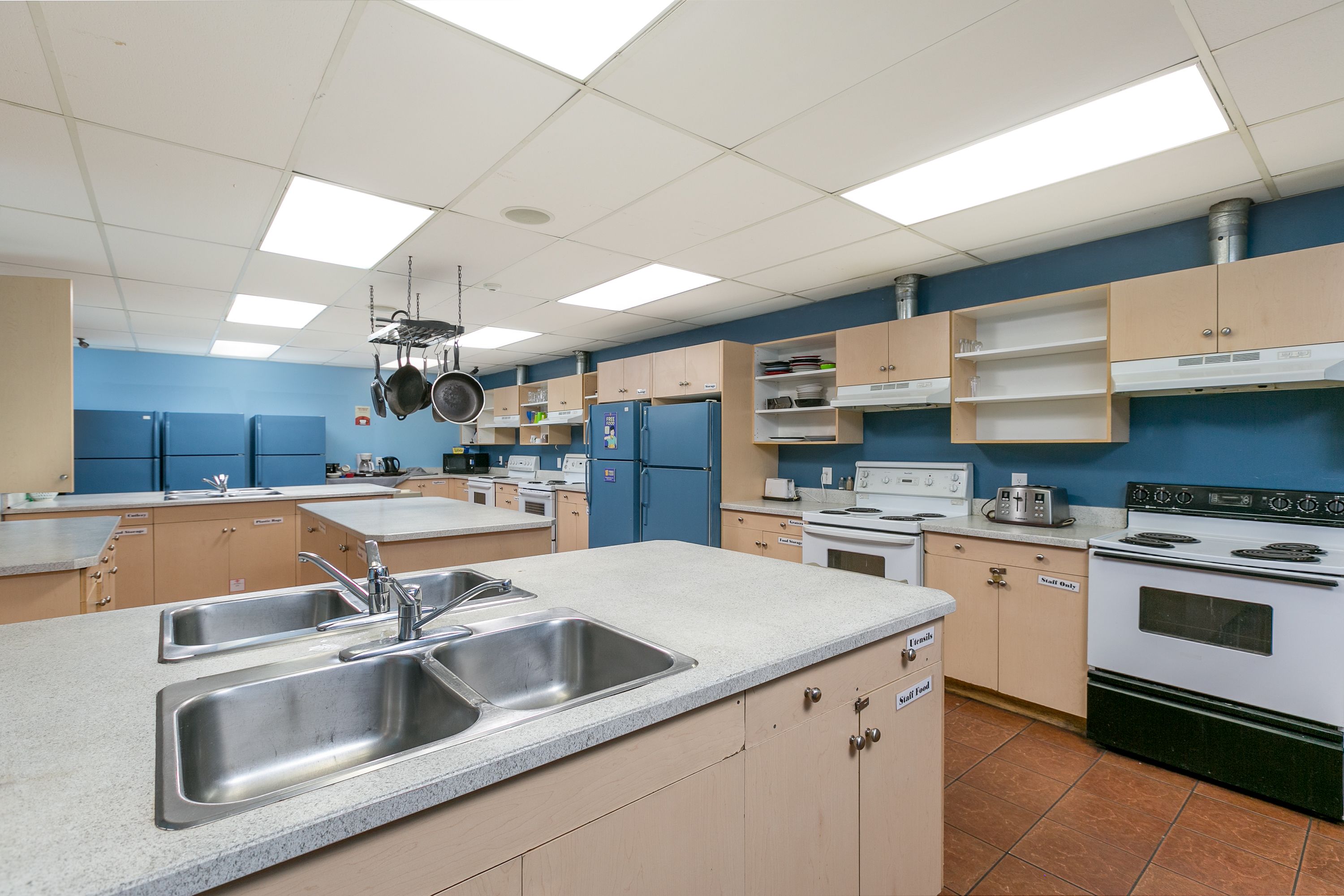 A kitchen with stainless steel sinks, a stove, and a microwave.