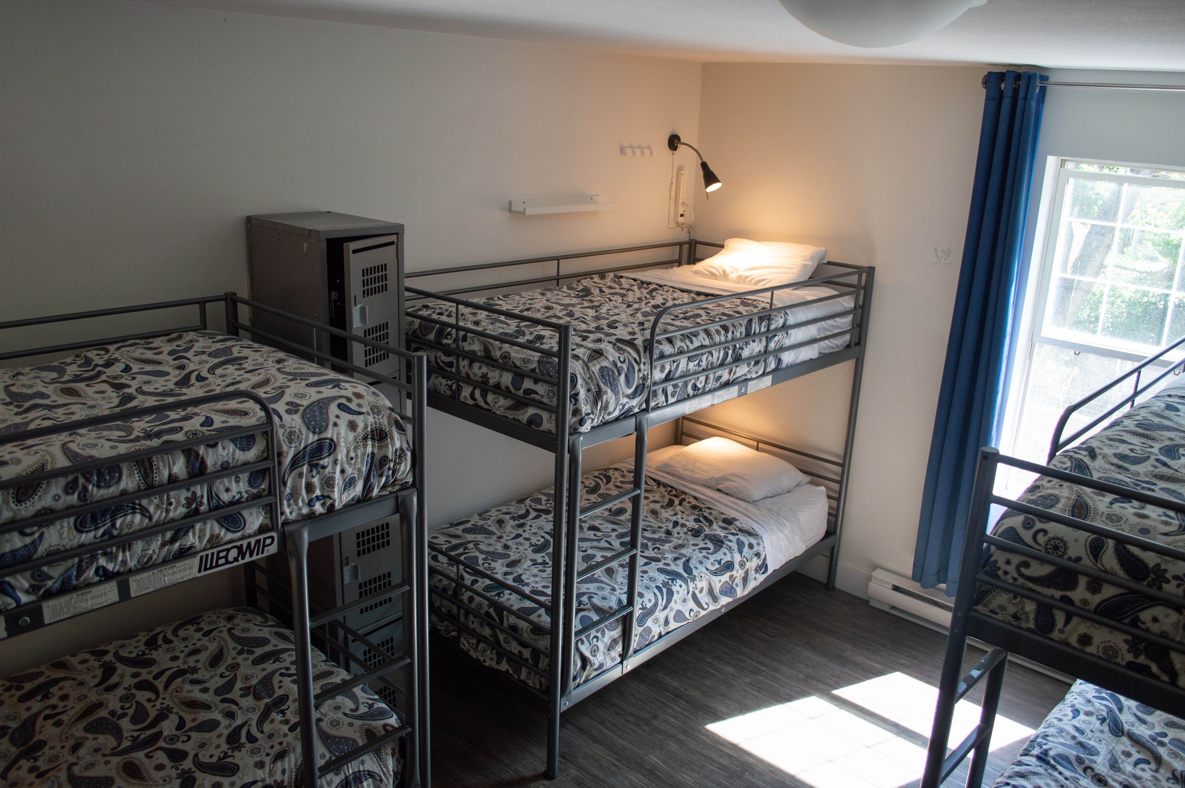 Ein Schlafsaalzimmer mit Etagenbetten, einem Schreibtisch und einem Fenster mit Vorhängen.
