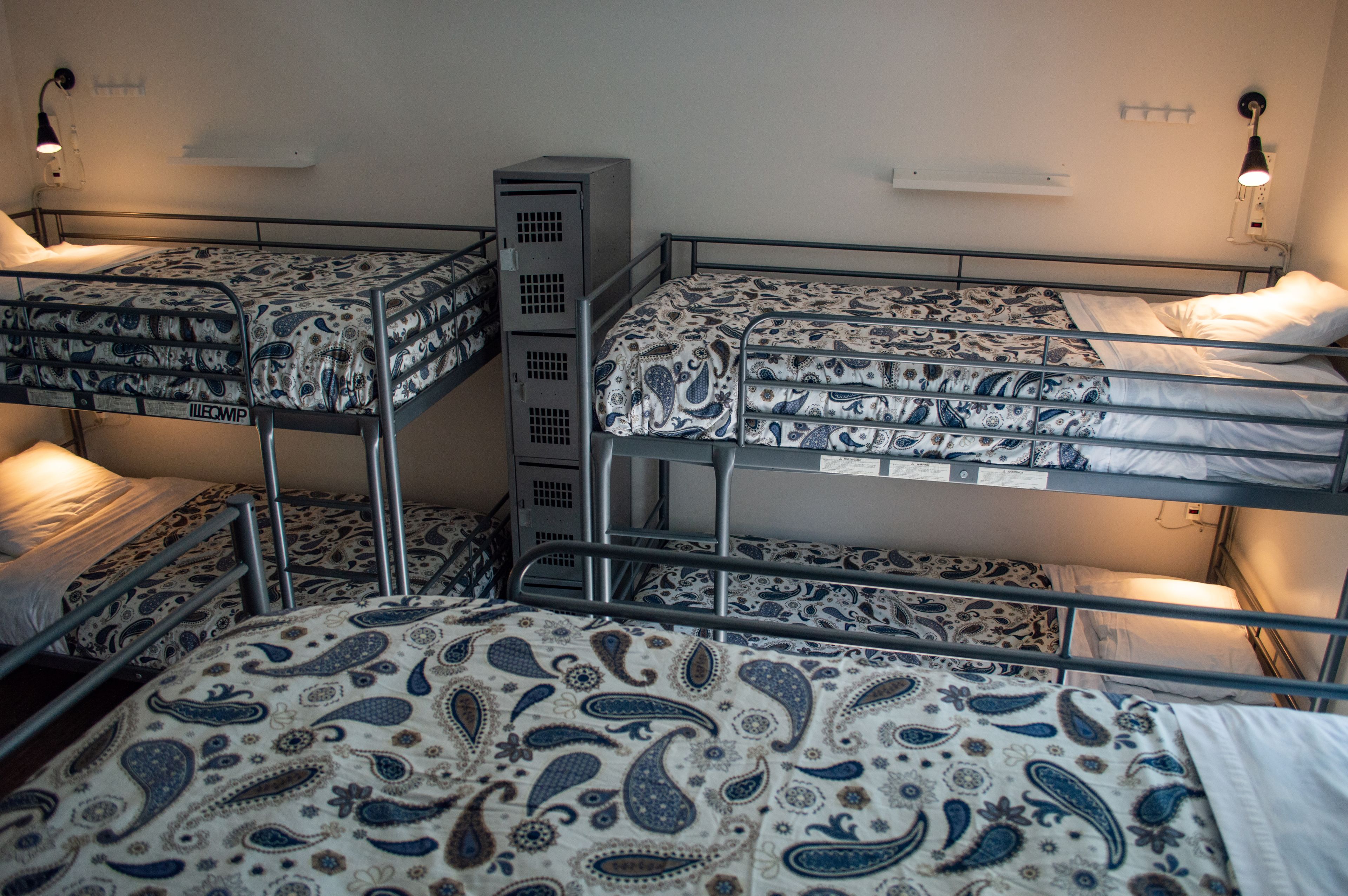 Een slaapzaal met stapelbedden, elk voorzien van beddengoed met een patroon.