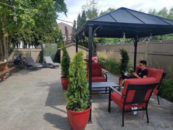 A patio with outdoor furniture, a pergola, and potted plants. -  HI Kelowna Hostel (Kelowna)