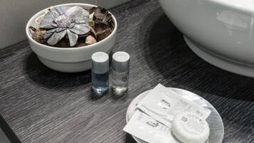 Ein Badezimmer mit Toilette, einer Schale mit getrockneten Blumen, zwei Flaschen mit Flüssigkeit und einem Seifenschälchen mit Seife und Zahnbürste.