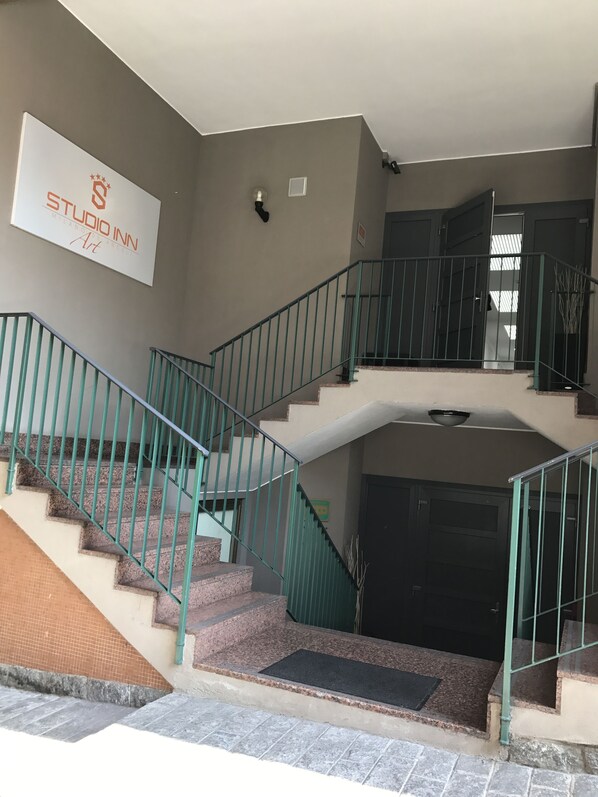 A staircase with green railings leading to an upper floor. A sign on the wall reads "STUDIO INN Art".