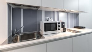 Une cuisine moderne dotée d’un évier en acier inoxydable, d’un four à micro-ondes et d’une machine à café posés sur le plan de travail.