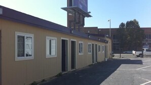 A building with multiple windows and doors, a parking lot, and a clear sky. - International Casa (Oakland)
