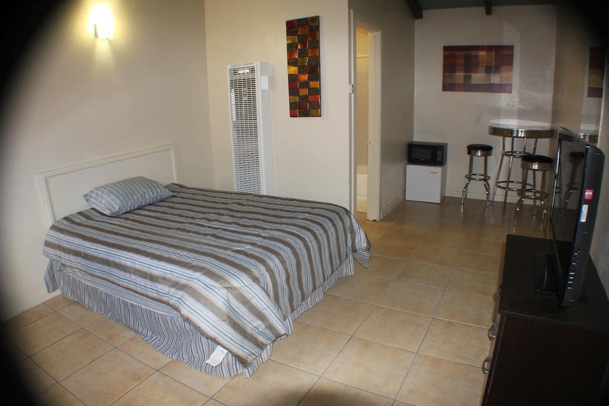 A bedroom with a bed, a heater, a small kitchenette, and a bar area.