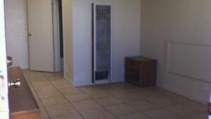 A room with a tiled floor, a door, a radiator, and a small wooden cabinet. - International Casa (Oakland)