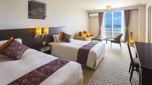 A hotel room with two beds, a desk, a chair, and a view of the ocean. - Cypress Resort Kumejima (Kumejima)