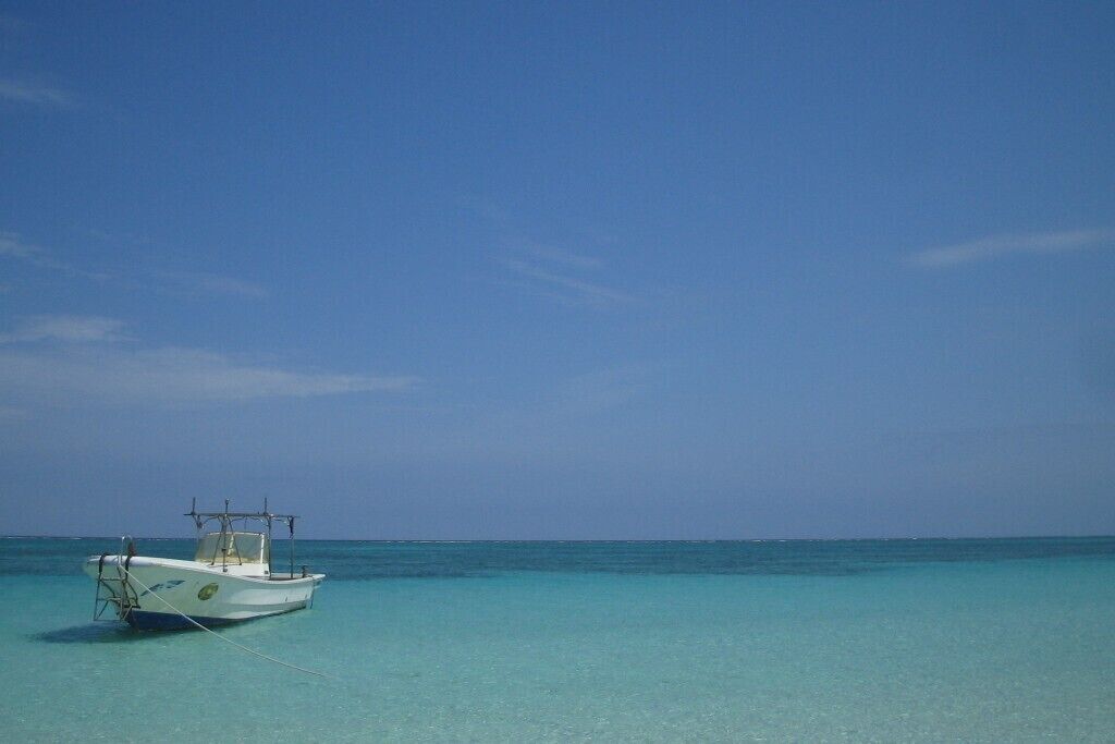 A boat anchored in clear turquoise water under a clear blue sky.