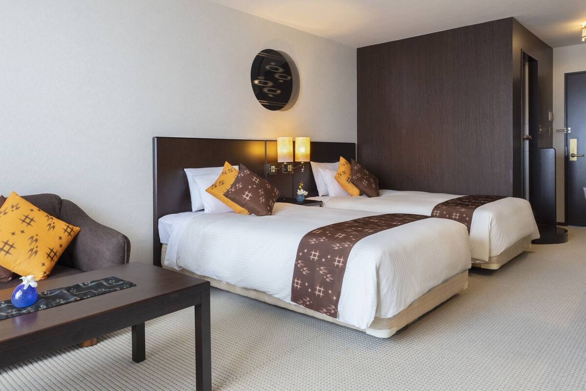 Ett hotellrum med två sängar, en soffa, ett soffbord och ett skrivbord.