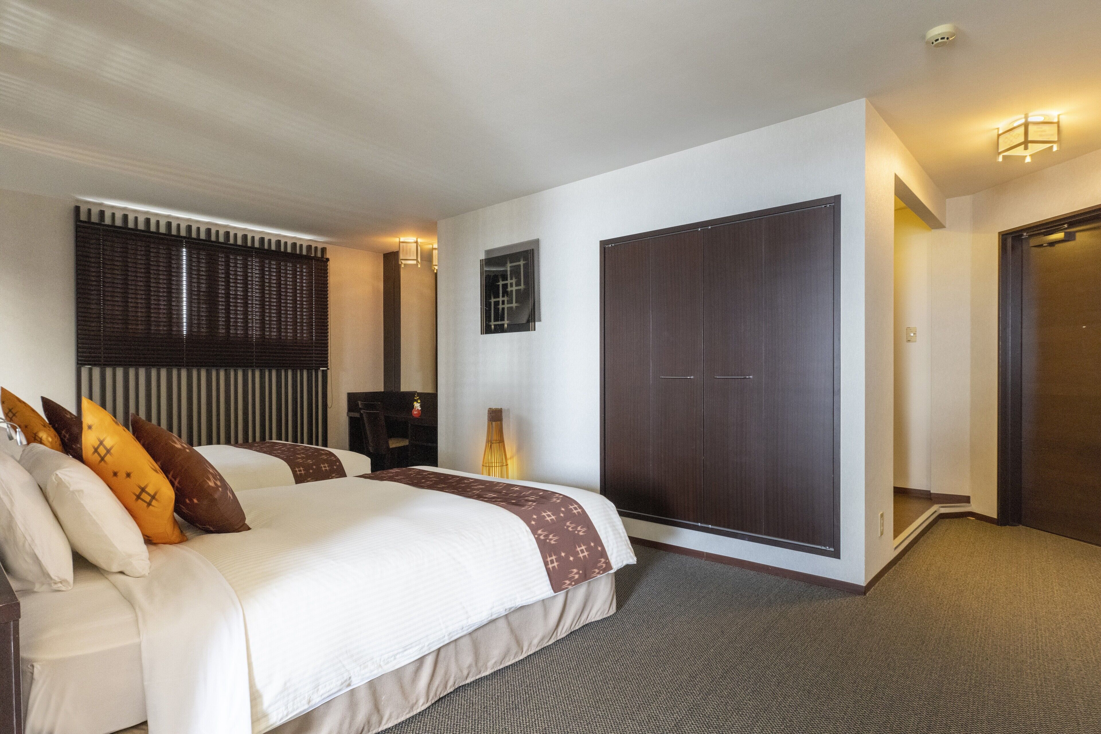Une chambre d’hôtel avec un grand lit, une armoire, un bureau et une chaise.
