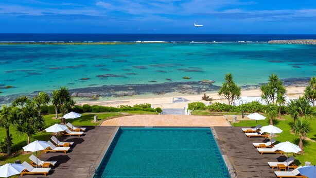 A pool with lounge chairs and umbrellas, overlooking a beach and ocean. - Cypress Resort Kumejima (Kumejima)