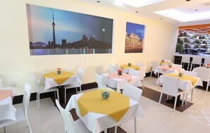 Comedor con mesas dispuestas para los huéspedes, con vista a la ciudad.