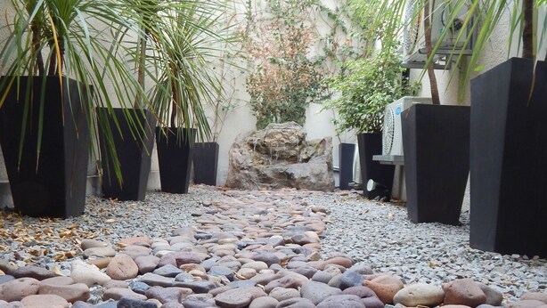 A pathway lined with large potted plants and a rock garden. - Puerto Mercado Hotel (Montevideo)