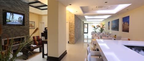 A modern dining area with a long white table, comfortable seating, and a stone accent wall.