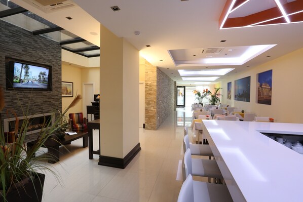 A modern dining area with a long white table, comfortable seating, and a stone accent wall.
