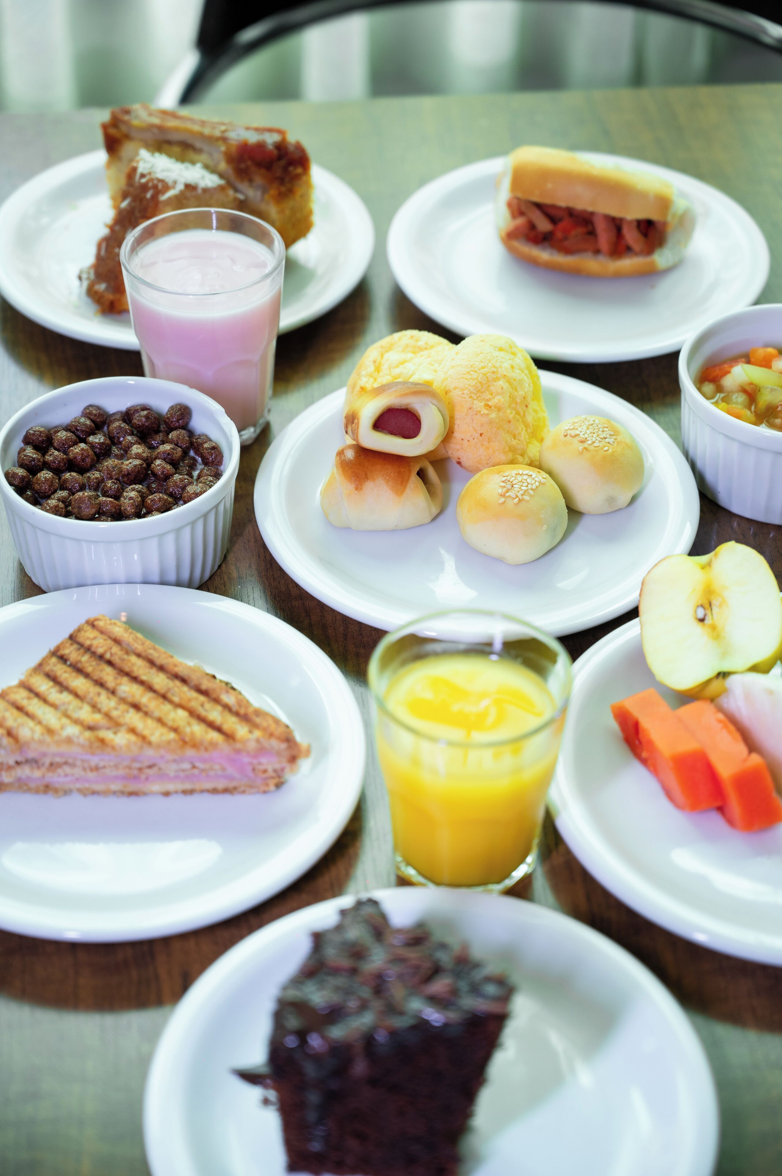 A table with various food items including a slice of cake, a sandwich, and a glass of juice.