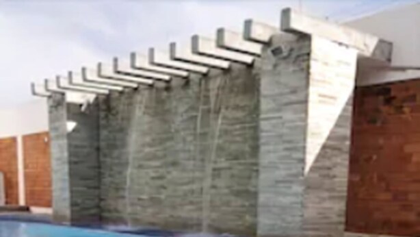 A swimming pool with a tiled floor and a stone wall with a metal railing. - Delcas Hotel (Cuiabá)