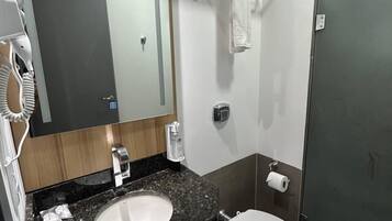 A modern bathroom with a granite countertop sink, a toilet, a hand dryer, and a towel rack.