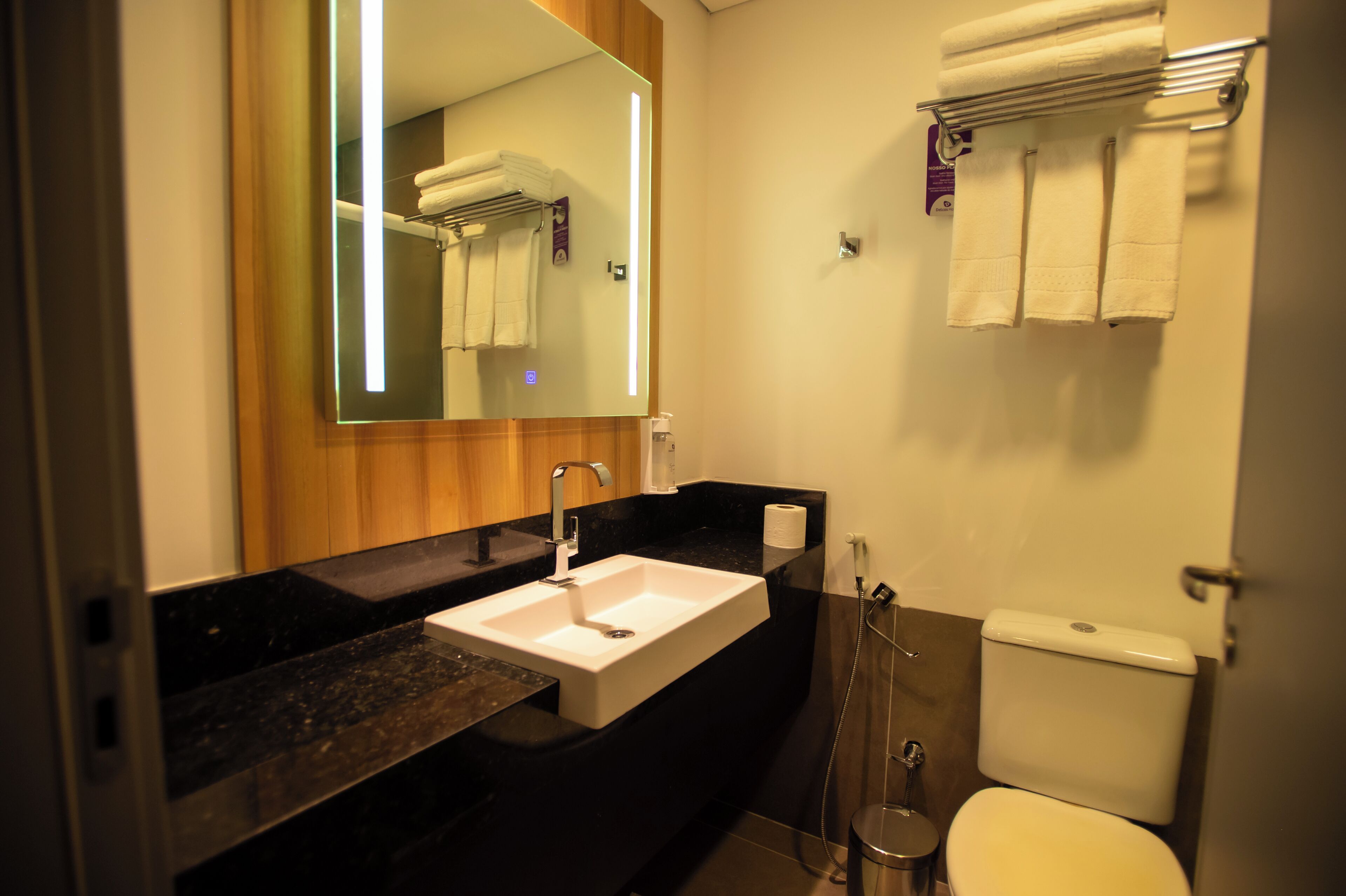 Un bany modern amb un mirall gran, un lavabo, un vàter i un escurapulides.