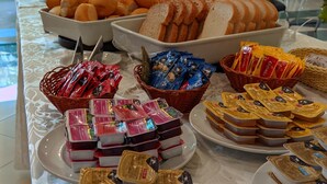 A buffet table with various food items including bread, pastries, and packaged snacks. - Delcas Hotel (Cuiabá)