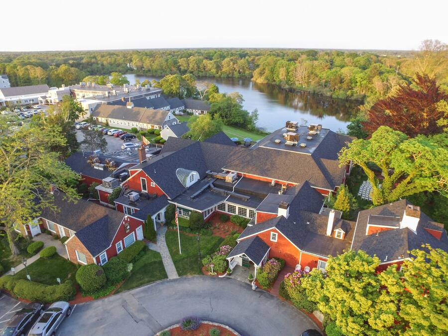 An aerial view of a residential area with houses, a river, and a parking lot.