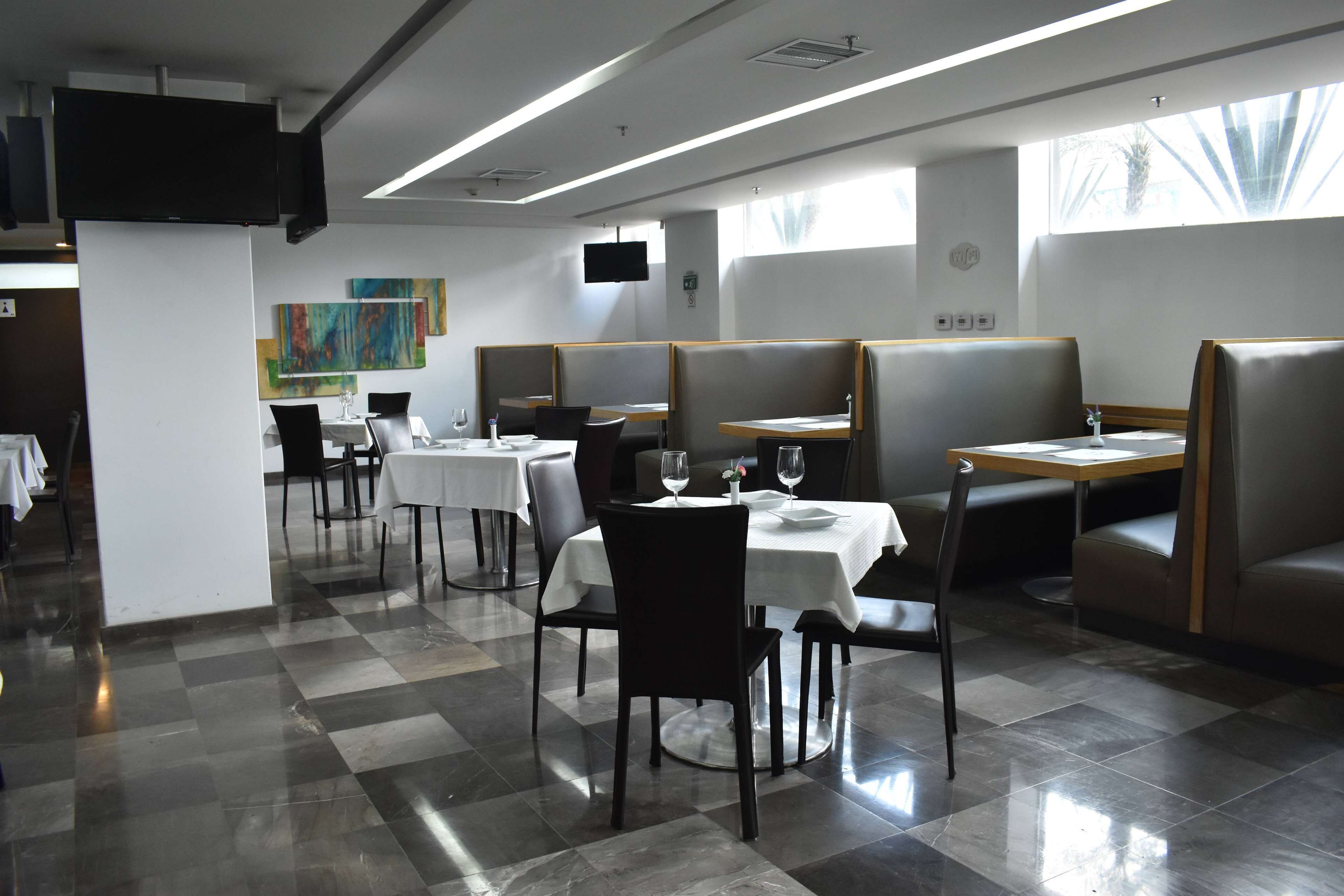 Un restaurant avec des banquettes, des tables et un sol carrelé.