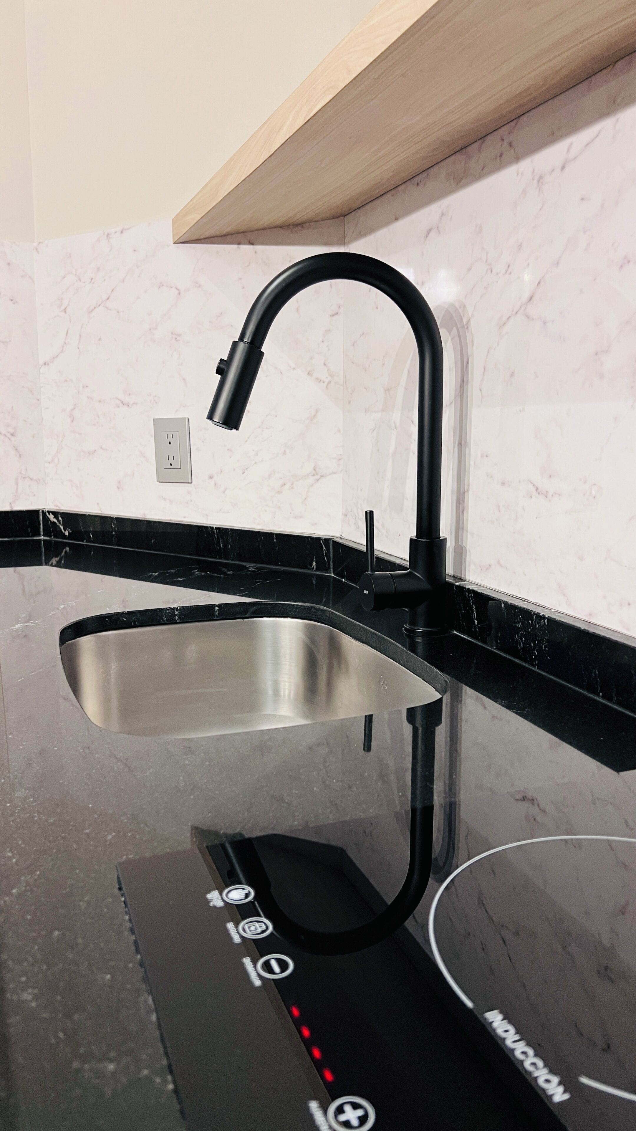 Una cocina moderna con un grifo negro, pileta de acero inoxidable y una encimera negra.