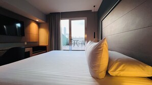 A hotel room with a bed, a TV, a desk, and a balcony with chairs. - Ramada by Wyndham Mexico City Santa Fe (Mexico City)
