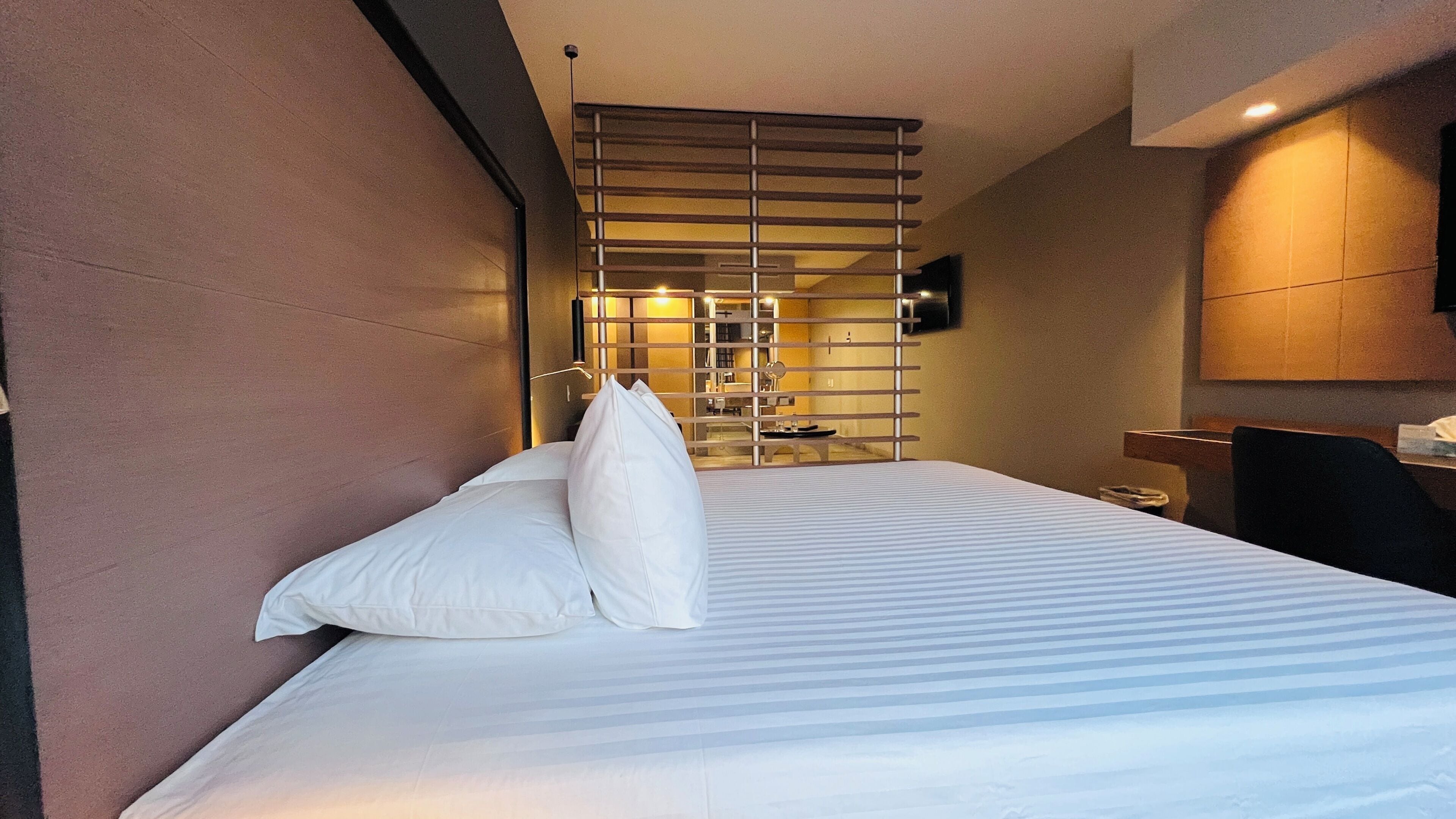 A hotel room with a bed, a TV mounted on the wall, and a modern design.