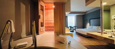A hotel room with a bathtub, a bed, a desk, and a chair.