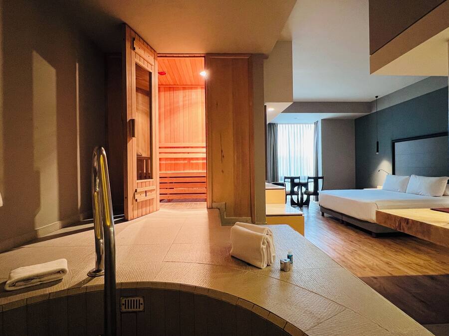 A hotel room with a bathtub, a bed, a desk, and a chair.