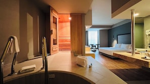 A hotel room with a bathtub, a bed, a desk, and a chair.