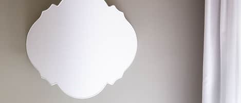 Un espejo blanco con borde ondulado sobre una pared.