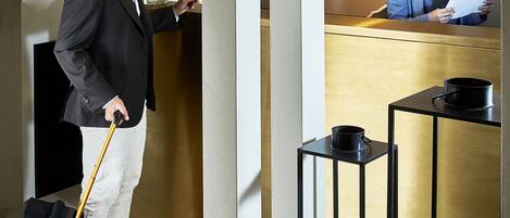 Zona de recepción de hotel con mostrador, un huésped a su lado y un recepcionista.
