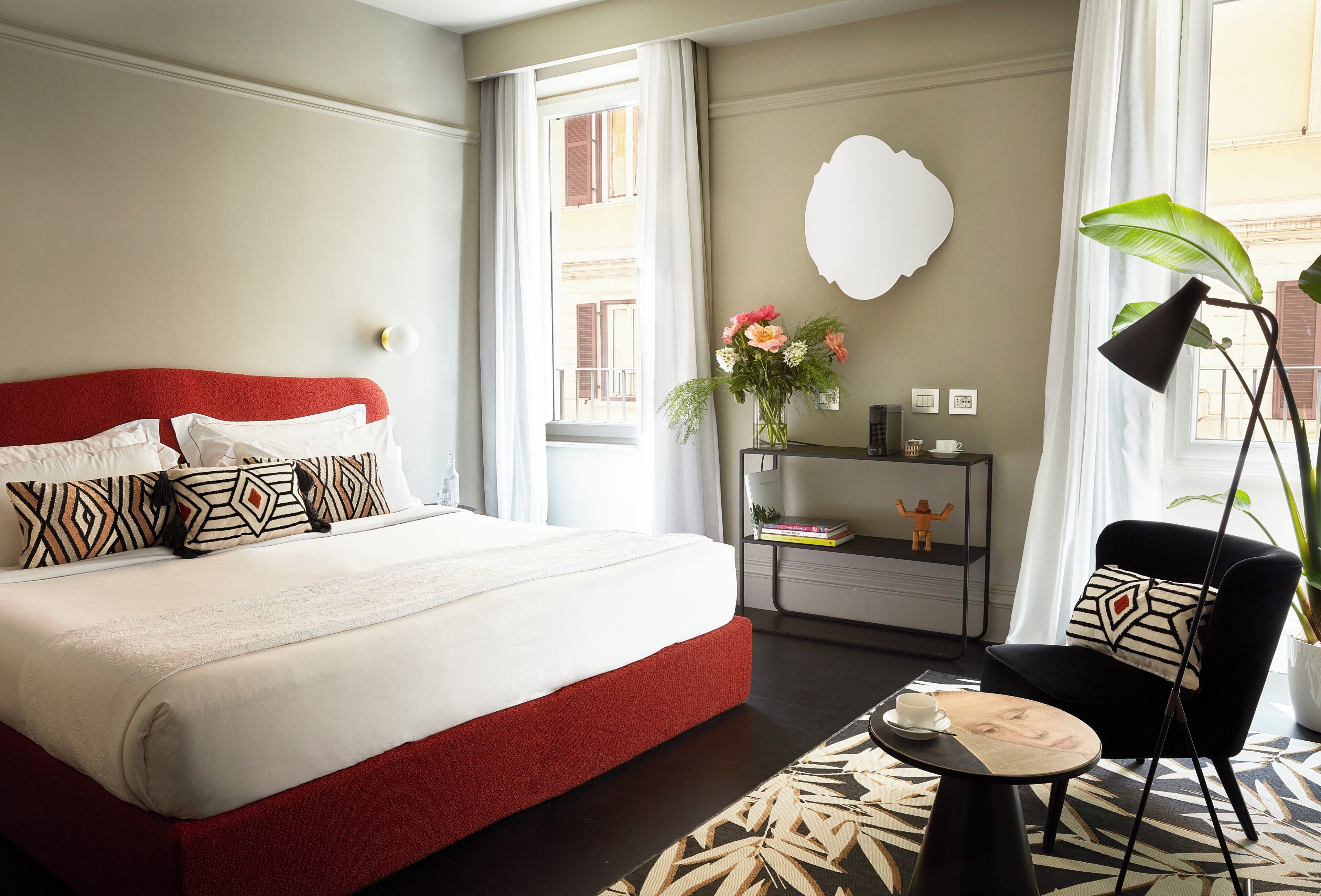 A hotel room with a large bed, a bedside table with a lamp, a chair, and a view of the outside.