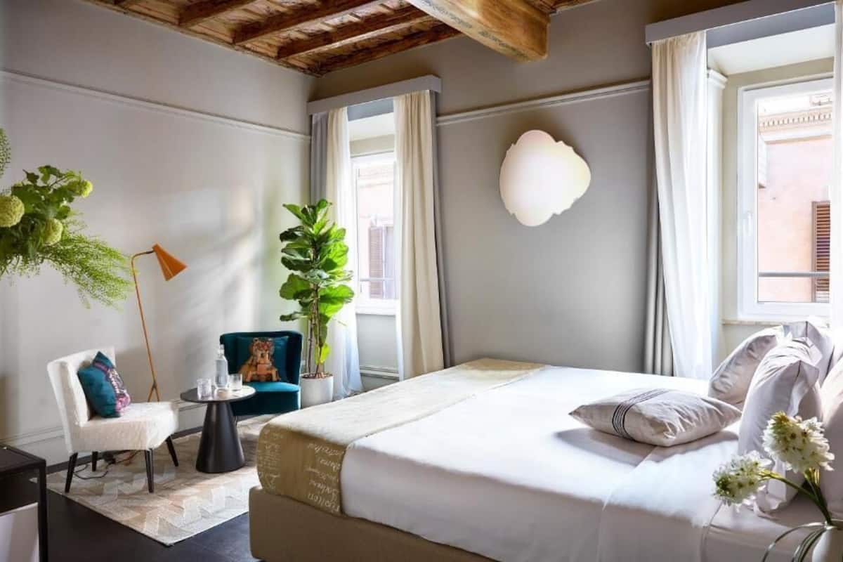 Una habitación de hotel con una cama, una silla, una mesita y una planta en maceta.