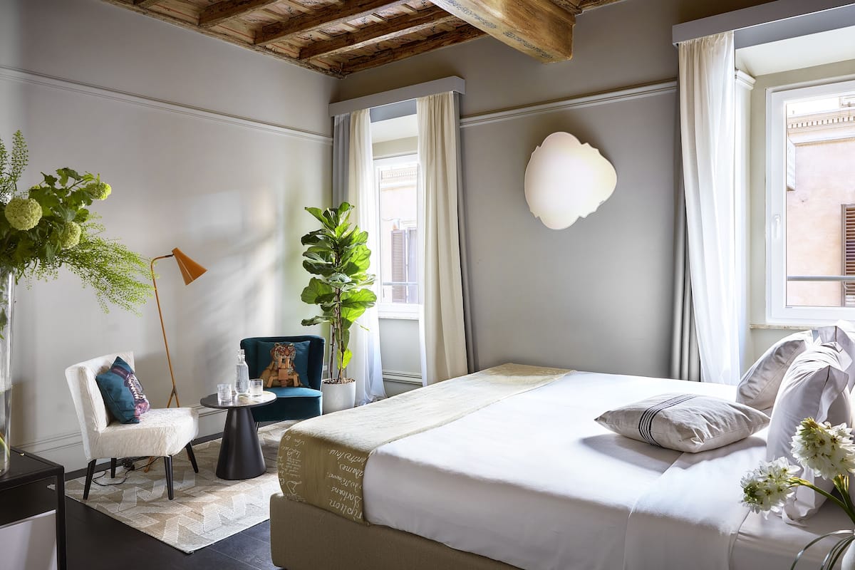 Un dormitorio con una cama grande, una silla, una mesita y una planta en maceta.