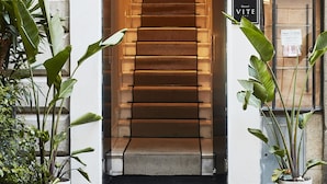 Entrada de un hotel con una escalera que conduce al interior, un felpudo con la inscripción 'Hotel Vite' y un cartel que indica el número 14.