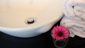 A bathroom sink with a white basin, a chrome faucet, and a rolled white towel beside it. - V Hotel (Kuala Lumpur)