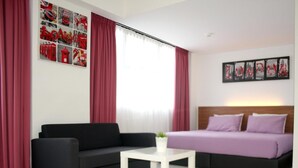 A modern hotel room with a black sofa, a white coffee table, and a bed with purple bedding. - V Hotel (Kuala Lumpur)