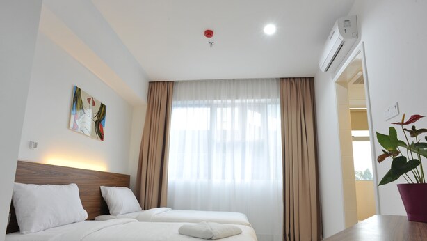 A hotel room with two beds, a large window with curtains, a ceiling light, an air conditioning unit, and a potted plant. - V Hotel (Kuala Lumpur)