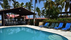 Una piscina al aire libre, sombrillas, sillones reclinables de piscina