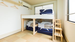 A bunk bed room with a window, wooden shelves, and a hanging rack.