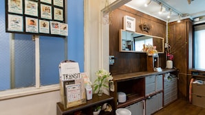 A room with a wooden cabinet, a mirror, a bulletin board with photos, and a vase with flowers.