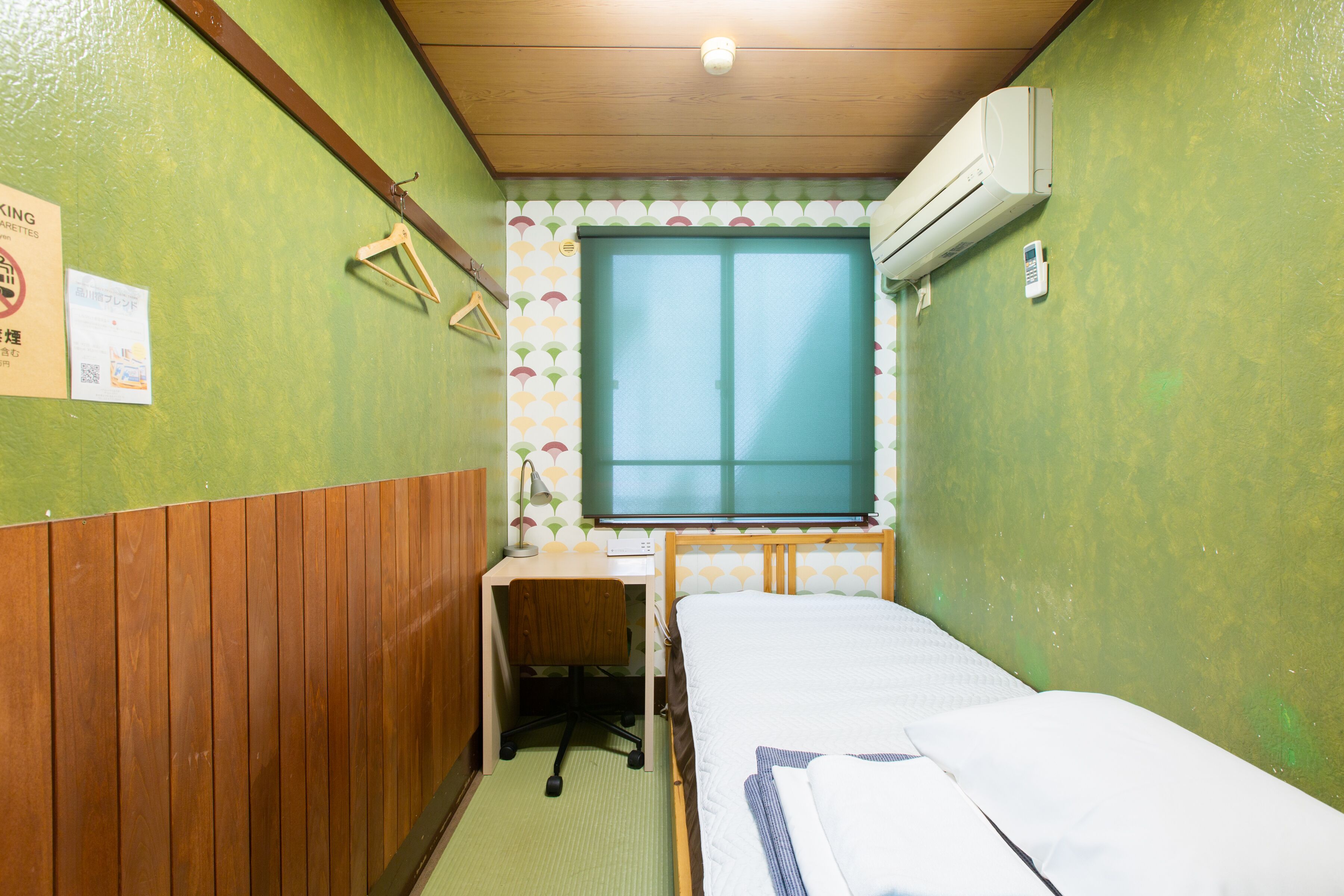 A small, compact room with a single bed, a desk, and a window.