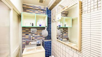 A bathroom with blue and white tiled walls, a mirror, and shelves with toiletries.