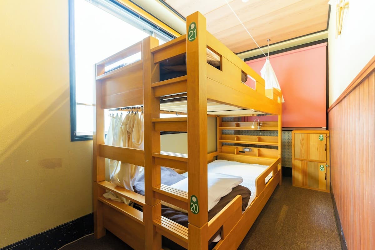 Habitació amb literes de fusta, un armari petit i una finestra.
