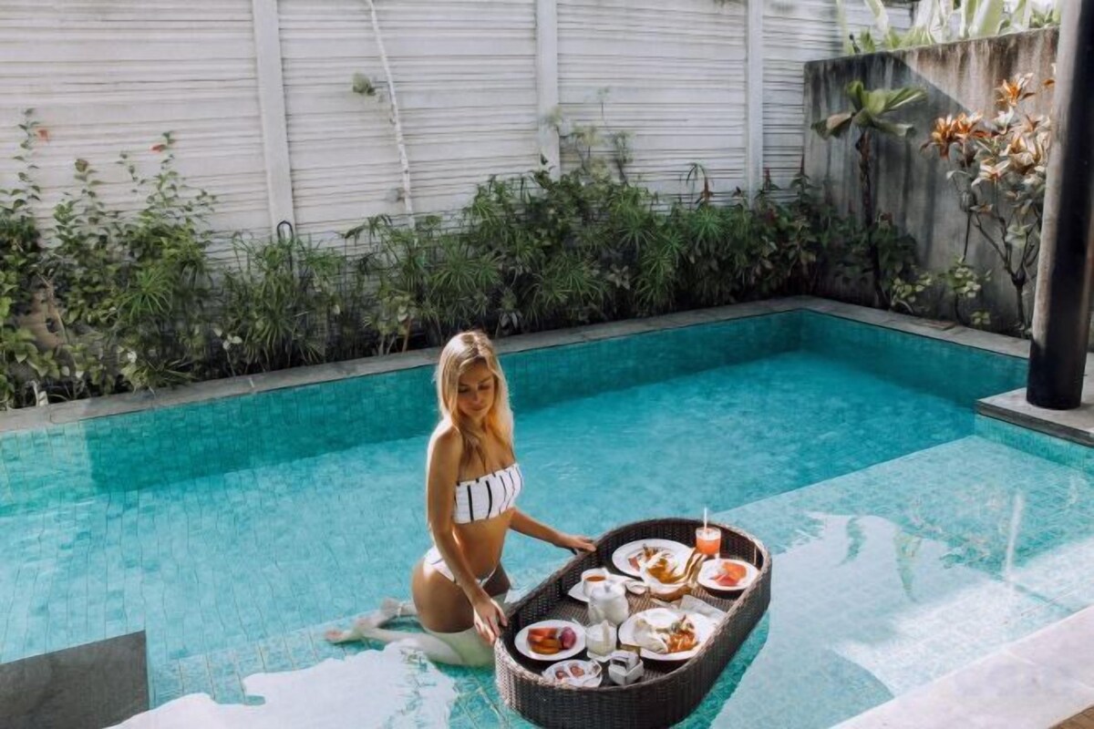 A person in a poolside setting with a tray of food and drinks.